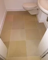 Natursteinplatten in warmen Beige- und Ockertönen im WC-Raum